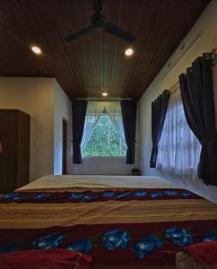 a bedroom with a bed with a ceiling fan and a window at Pine ridge homestay kuttikanam in Pīrmed