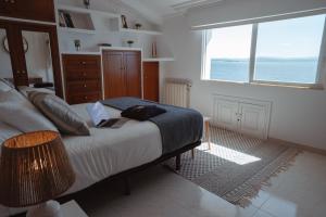 a bedroom with a bed with a view of the ocean at La Marisol Ribeira in Ribeira