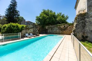 a swimming pool in front of a stone wall at Château Puybarban in Puybarban