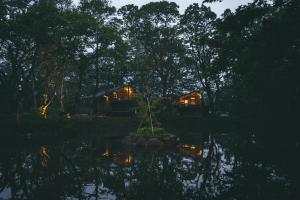 a couple of tents in a forest near a body of water at Earthboat Nasu - Glamping Cabin with Private Wood-Fired Sauna & Onsen, Pet-Friendly & Cage-Free in Nasu +134 photos