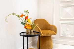 a vase of flowers on a table next to a chair at Dama Luxury Suites Pompei in Pompei