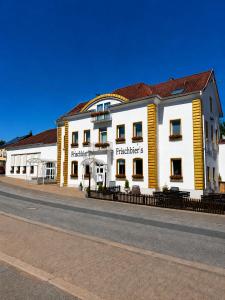a white and yellow building on the side of a street at Frischbier's Gästezimmer in Schmelz-Primsweiler