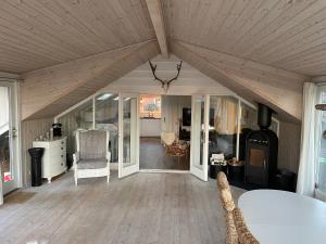 a living room with a wooden ceiling and a room with a table at Charming House Close To The Beach in Gedser