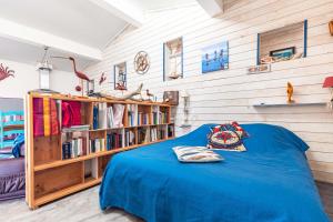 a bedroom with a blue bed and a book shelf at Petite Maison Typique in La Cotinière