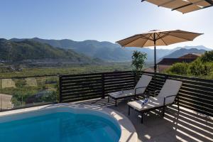 a swimming pool with two chairs and an umbrella at Apartman Klara in Vrgorac