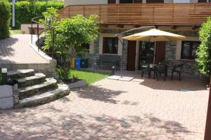 a patio with an umbrella and a table and chairs at TAVANIs HOUSE in Delebio