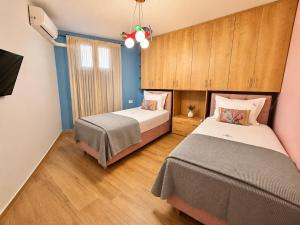two beds in a bedroom with blue walls and wooden floors at Jasemina Luxury Apartment in Agios Nikolaos +24 photos