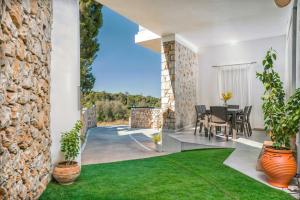 a patio with a table and chairs and a stone wall at Jasemina Luxury Apartment in Agios Nikolaos