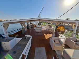 a boat with chairs and a table on the water at The Nile Dahabiya Lodge in Luxor