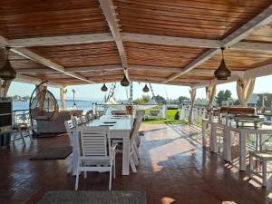a restaurant with white tables and chairs and the ocean at The Nile Dahabiya Lodge in Luxor