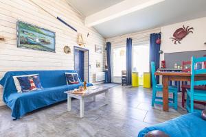 a living room with a blue couch and a table at Petite Maison Typique in La Cotinière