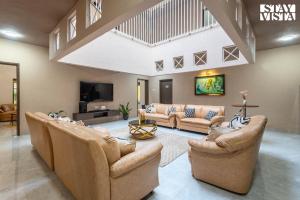 a large living room with couches and a tv at Hindavi Green Escape by VEO - Part of StayVista with Bonfire, BBQ & Pool in Pune