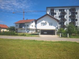 a white house in front of a large building at Apartman Knežević in Donja Varoš