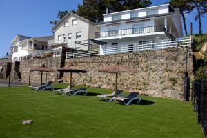 a group of lawn chairs and umbrellas in front of a building at La Marisol Ribeira in Ribeira