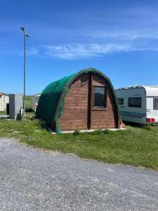 a tent sitting in the grass next to a trailer at Cois Farraige Glamping Pod in Milltown Malbay