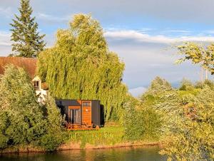 a house on the shore of a river with a tree at Ezy House by Tiny Away in Ézy-sur-Eure