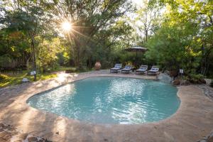 a pool with chairs and an umbrella in a yard at Masuwe Lodge in Victoria Falls