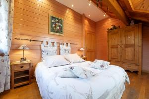 a bedroom with a white bed with a wooden wall at Chalet Du Pont Des Fées in Gérardmer