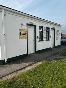 a white building with doors and signs on it at Cois Farraige Glamping Pod in Milltown Malbay