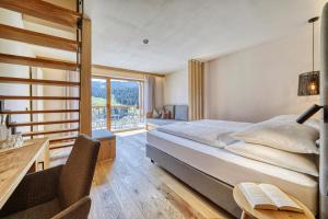 a bedroom with a bed and a desk and a window at Brunelle Seiser Alm Lodge in Alpe di Siusi +119 photos