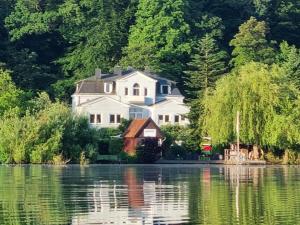 a large house sitting on the shore of a lake at Pension Seeschlösschen in Mölln