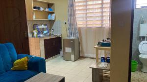 a living room with a blue couch and a kitchen at Margin Diani in Ukunda