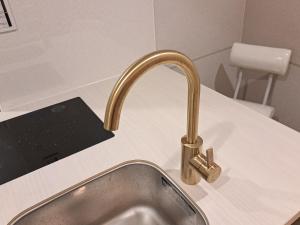 a kitchen sink with a gold faucet on a counter at お部屋に露天風呂 自分専用の湯船に新鮮な熱海温泉を入れる贅沢 新築美麗AtamiOnsenApart104 in Atami +10 photos