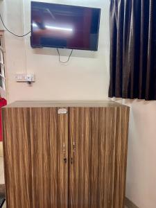 a television on a wall above a wooden cabinet at Leo Stays in Bangalore