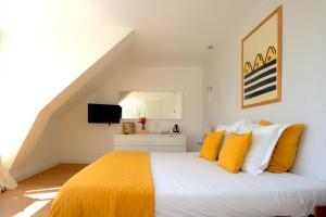 a bedroom with a bed with yellow and white pillows at La Villa des Sables in Concarneau