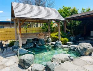 a small pond with rocks and a gazebo at 雪の宿 in Numata