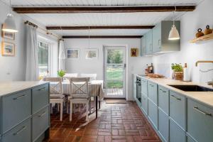 a kitchen with blue cabinets and a table with chairs at 591-Snedsted-Stenbjergvej-28 in Snedsted