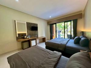 a bedroom with two beds and a couch and a mirror at Puri Bali Hotel in Lovina