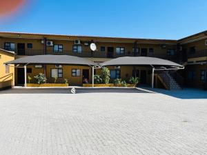 a building with two large umbrellas in a parking lot at Otam-Check Guest House in Ondangwa