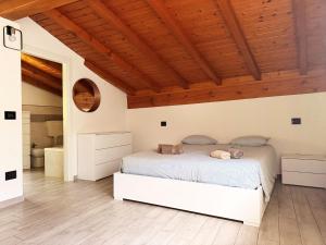 a bedroom with a white bed and wooden ceilings at Casa vacanze Adri in Faggeto Lario 