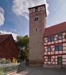 einem hohen Backsteingebäude mit einem Uhrturm in der Unterkunft Ferienwohnungen Am Butterturm in Bad Langensalza