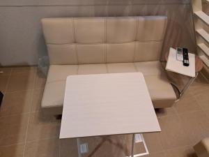 a coffee table next to a couch with a remote control at お部屋に露天風呂 自分専用の湯船に新鮮な熱海温泉を入れる贅沢 新築美麗AtamiOnsenApart104 in Atami