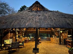a large straw hut with chairs and tables and chairs at Masuwe Lodge in Victoria Falls