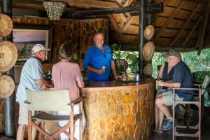 a group of people sitting at a bar at Masuwe Lodge in Victoria Falls