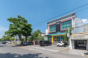 a building with cars parked in front of a street at Sans Hotel Good Wish Semarang in Jomblang