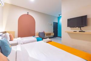 a room with two beds and a flat screen tv at Sans Hotel Good Wish Semarang in Jomblang