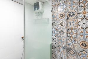 a bathroom with a tile wall with a shower at Sans Hotel Good Wish Semarang in Jomblang +23 photos