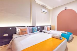 a bedroom with two beds with pillows at Sans Hotel Good Wish Semarang in Jomblang