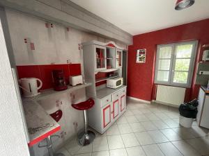 a kitchen with red walls and white cabinets at Chez KUD in Bourbon-Lancy