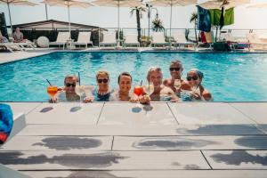 a group of people holding drinks in a swimming pool at Hotel Adlon in Lido di Jesolo