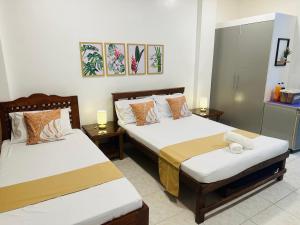 a bedroom with two beds and two lamps on tables at JORA Studio Apartment 1-B in Dagupan