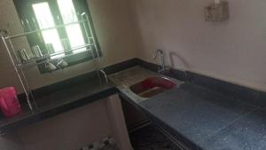 a kitchen with a red sink and a window at The Hojai Farmland in Hāflong