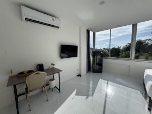 ein weißes Zimmer mit Schreibtisch, Bett und Fenster in der Unterkunft Keya hotel samui in Plai Laem