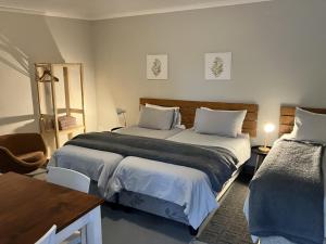 a bedroom with two beds and a table and a chair at Vlettershof Guest House in Robertson
