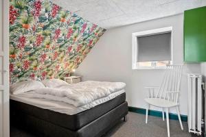 a bedroom with a bed with a tropical wallpaper at 4231-Stege-Nymarksvej-21 in Stege