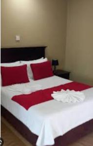 a large white bed with red pillows in a bedroom at Maun self-catering unit in Maun